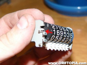 Take the mileage odometer in hand and pry the metal tab up slightly with a small flat head.