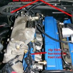 Attach the air line from the charge pipe to the AAC, FICD assembly using a 3/8" hose.  (This image also shows zip ties holding an already modified harness to the fuel rail.)