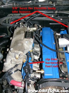Attach the air line from the charge pipe to the AAC, FICD assembly using a 3/8" hose.  (This image also shows zip ties holding an already modified harness to the fuel rail.)