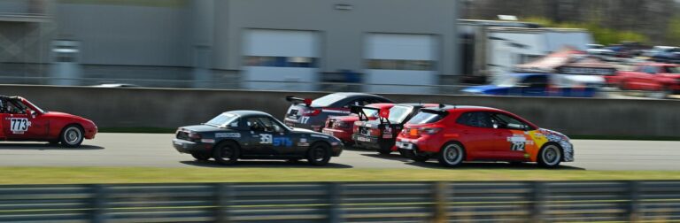Feature image for https://driftopia.com/blog/2024/04/02/entertaining-myself-at-the-national-corvette-museum/ featuring cars going four wide into turn one at the race start.