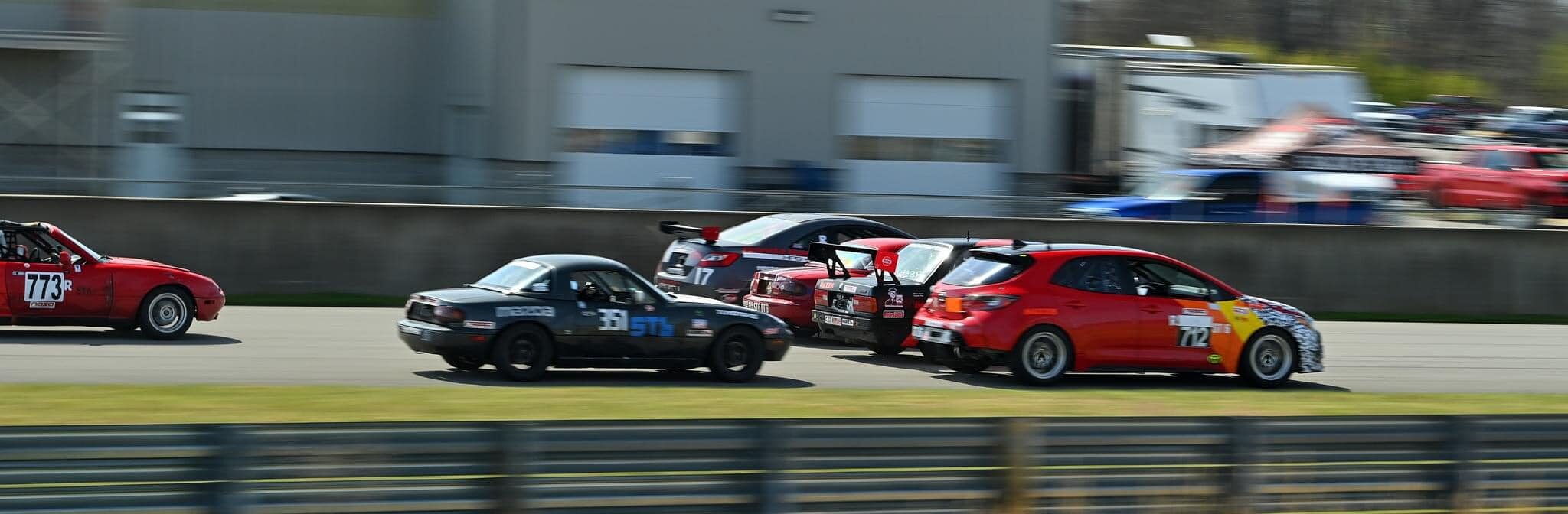 Feature image for https://driftopia.com/blog/2024/04/02/entertaining-myself-at-the-national-corvette-museum/ featuring cars going four wide into turn one at the race start.