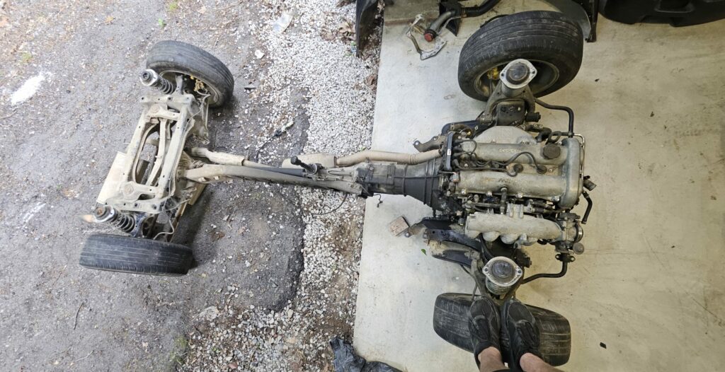 The subframe and drivetrain removed as a single piece from the 1991 NA Mazda Miata.