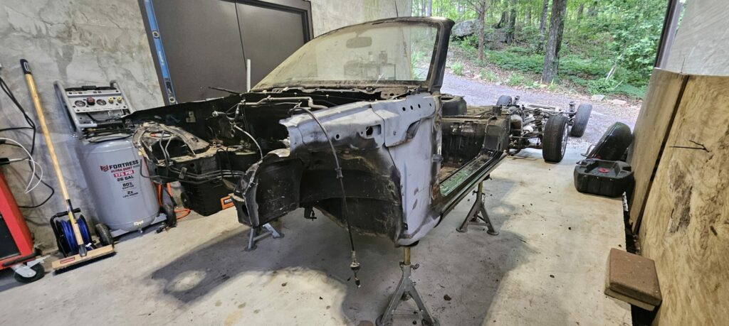 Bare chassis on jack stands after drivetrain removal on the 1991 NA Mazda Miata