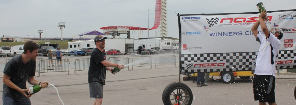 Three 944 Spec racers celebrating on the podium at Circuit of the Americas.