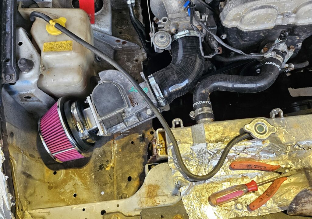 The 1.6l NA Miata cold side intake in the passenger side headlight.