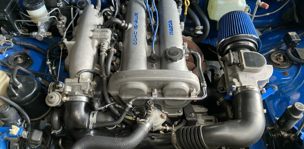 1991 Miata NA engine bay adapted to spec miata with a cone filter after the afm.