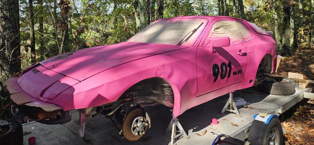 The repainted #901 944 Spec painted in matte hot pink while sitting on jack stands on the trailer.