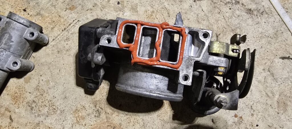 RTV Silicone applied around the throttle body ports of the NA Miata after ISCV removal.