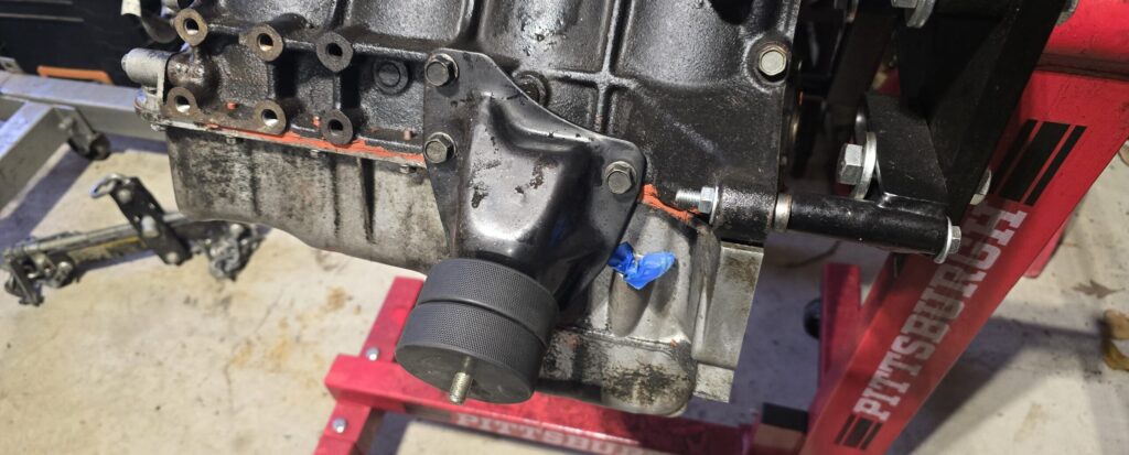 Hockey puck motor mounts loosely attached to the block of the NA Miata.